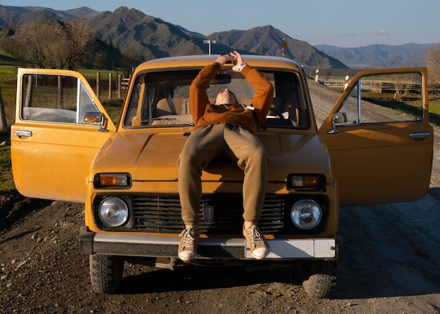 Full shot man laying on car