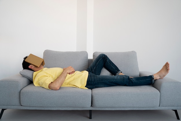 Full shot man laying on couch with book