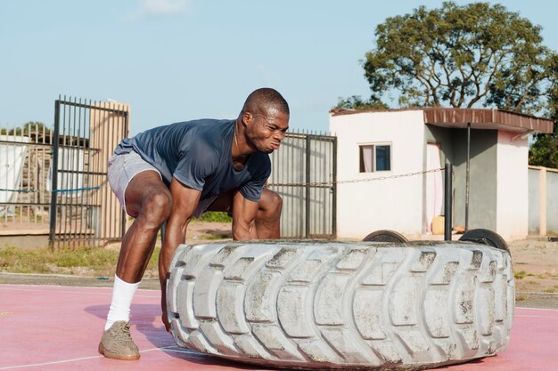 Full shot man lifting heavy wheel