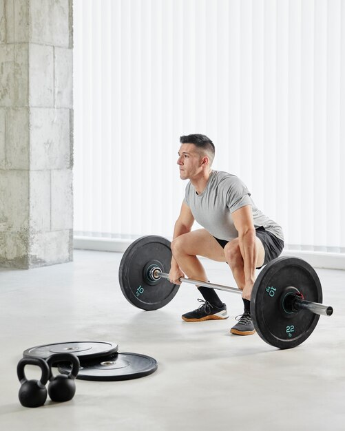 Full shot man lifting weights indoors