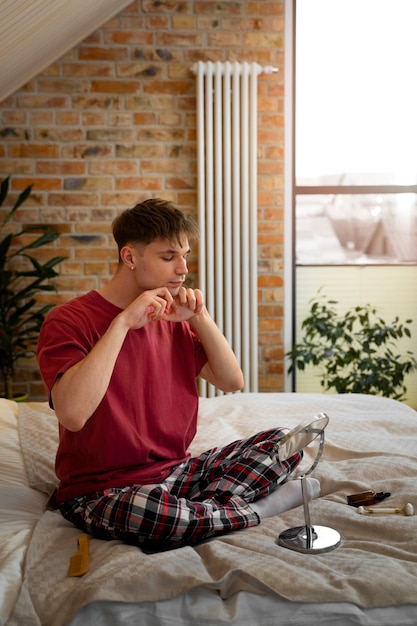 Foto gratuita uomo a figura intera che massaggia il viso a casa