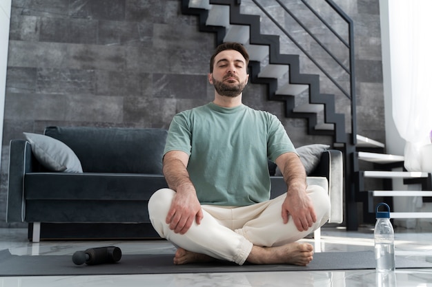Full shot man meditating on yoga mat