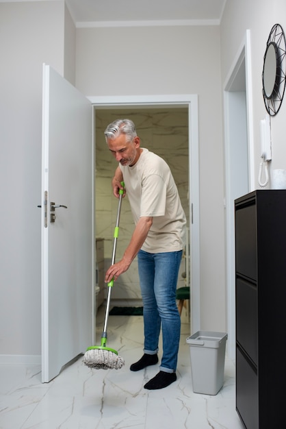 Full shot man mopping the floor