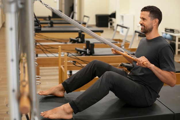 Full shot man  in pilates reformer class