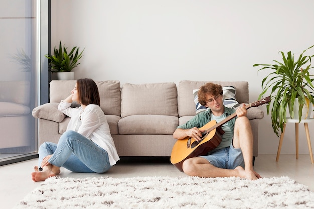 Full shot man playing the guitar indoors