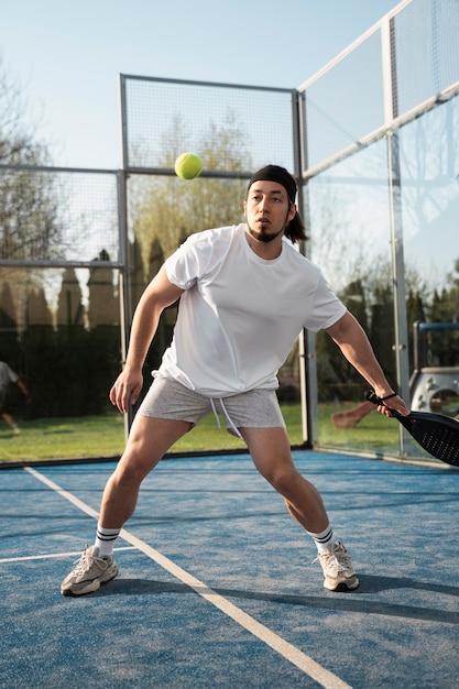 Бесплатное фото Полный выстрел мужчина играет в паддл-теннис на открытом воздухе