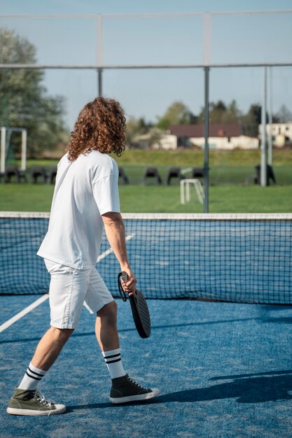 Full shot man playing paddle tennis