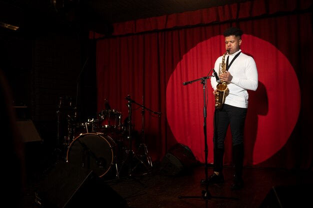 Full shot man playing the saxophone