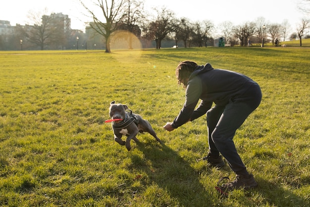 Foto gratuita uomo a figura intera che gioca con il cane all'aperto
