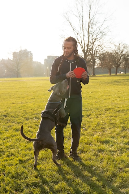 Free photo full shot man playing with dog outdoors