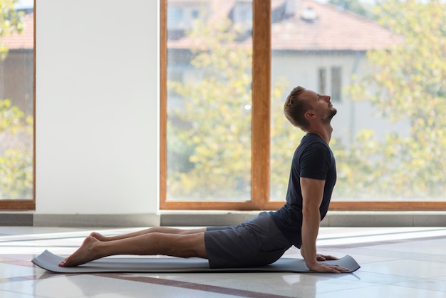 Full shot man practicing cobra pose indoor