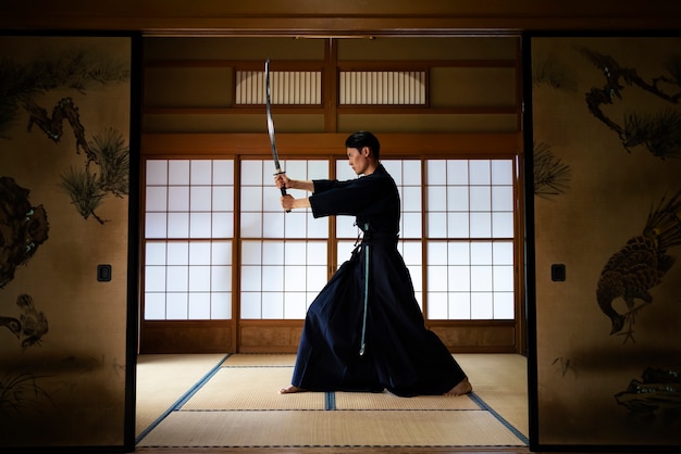 Full shot man practicing with sword indoors