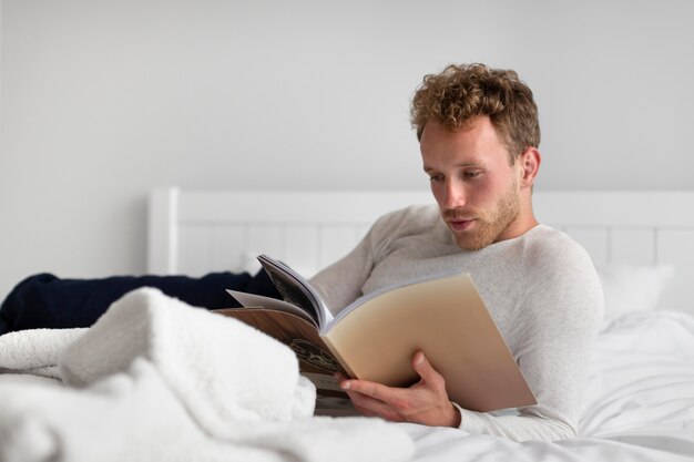 寝室で本を読んでいるフルショットの男