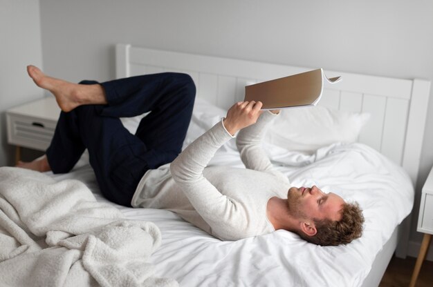 Full shot man reading book at home