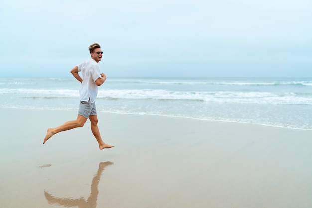 Free photo full shot man running on the beach