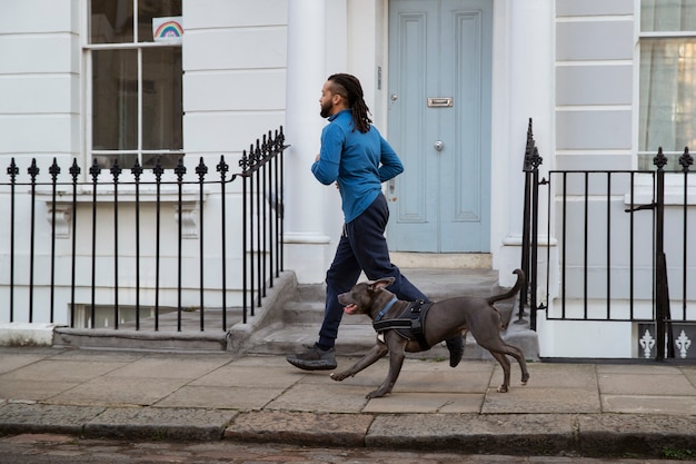 Foto gratuita uomo a figura intera che corre con il cane all'aperto