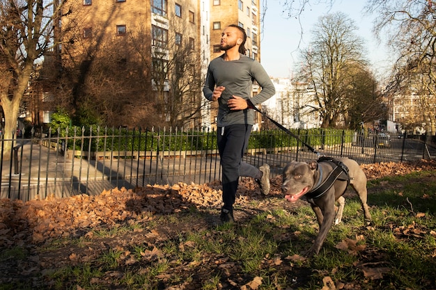 Foto gratuita uomo a figura intera che corre con il cane all'aperto