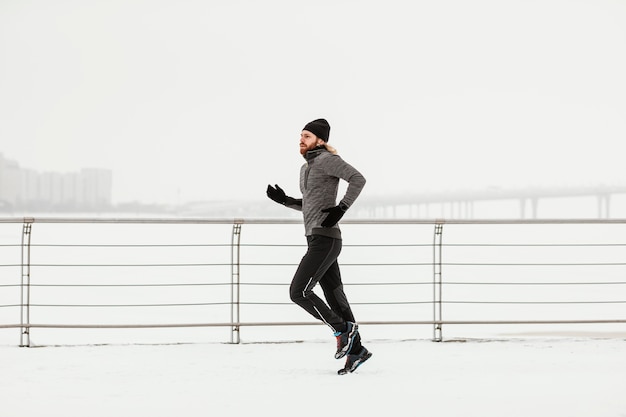 Full shot man running with snow