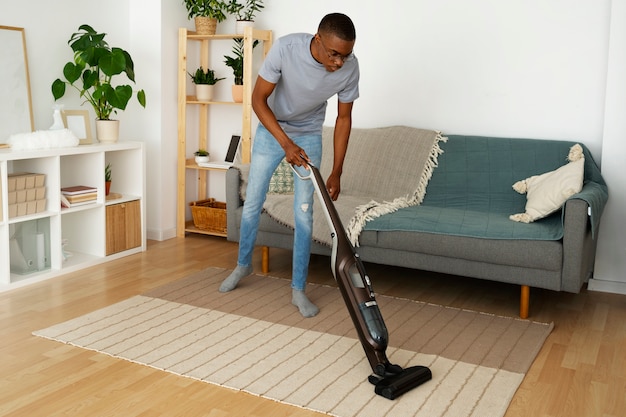 Free photo full shot man servant vacuuming floor