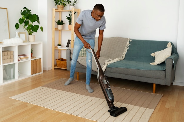 Full shot man servant vacuuming floor
