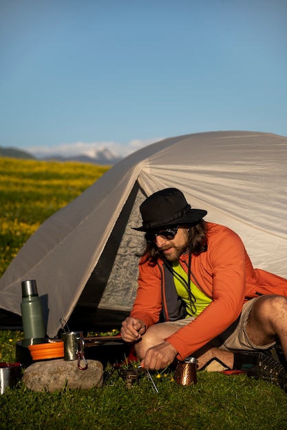 Free photo full shot man sitting by the tent