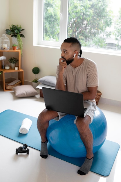 Full shot man sitting on gym ball