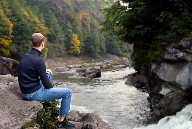 Full shot man sitting on rock