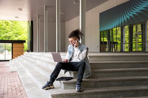 Full shot man sitting on stairs with laptop