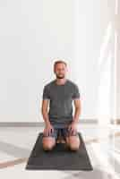 Free photo full shot man sitting on yoga mat