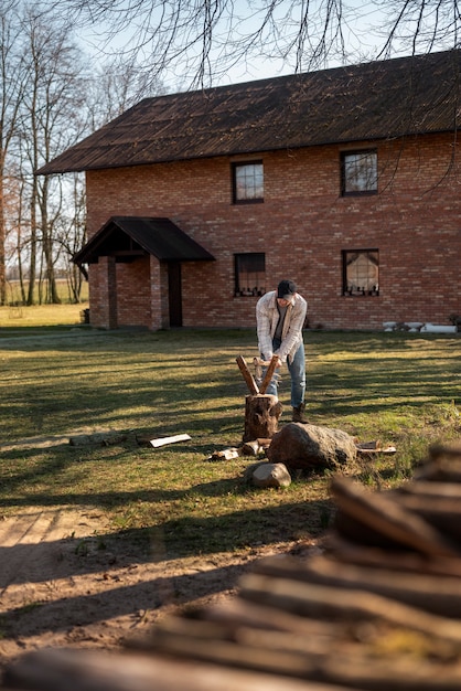 Foto gratuita uomo del colpo pieno che spacca il legno con l'ascia