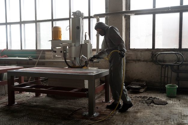 Free photo full shot man spraying powder paint from a gun