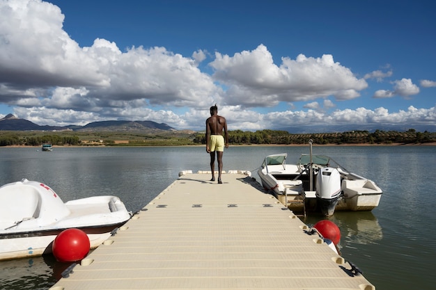 Free photo full shot man standing by the lake