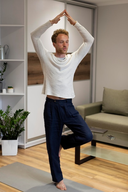 Full shot man standing on one leg at home