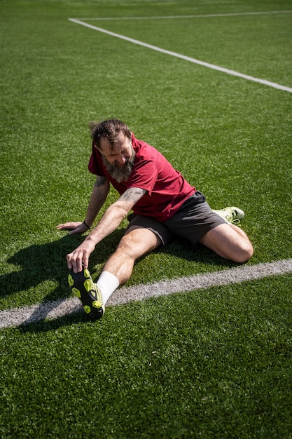 Foto gratuita uomo a tutto campo che si estende sul campo