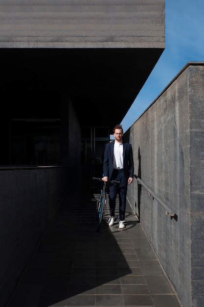 Full shot man in suit with bicycle going to job