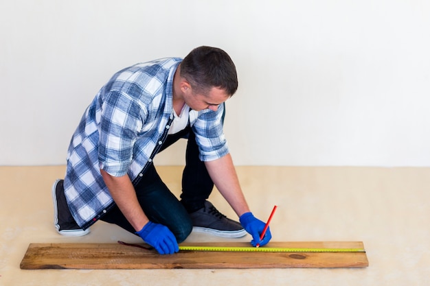 Full shot of man taking measure on wood