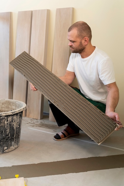 Full shot man tiling floor