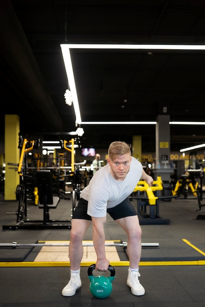 Free photo full shot man training with blue kettlebell