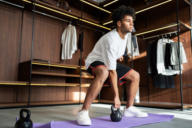 Full shot man training with kettlebell in closet