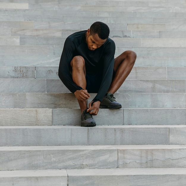 Free photo full shot man tying his shoelace