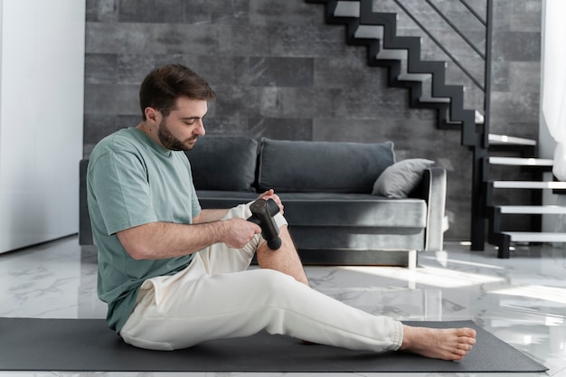 Full shot man using massage gun