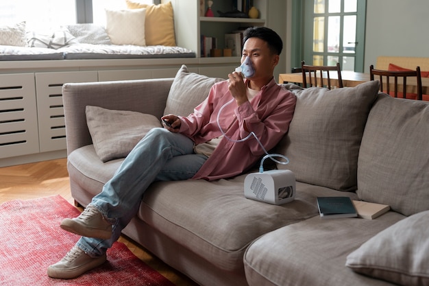 Full shot man using nebulizer at home