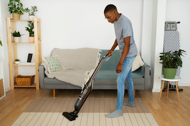 Full shot man vacuuming floor