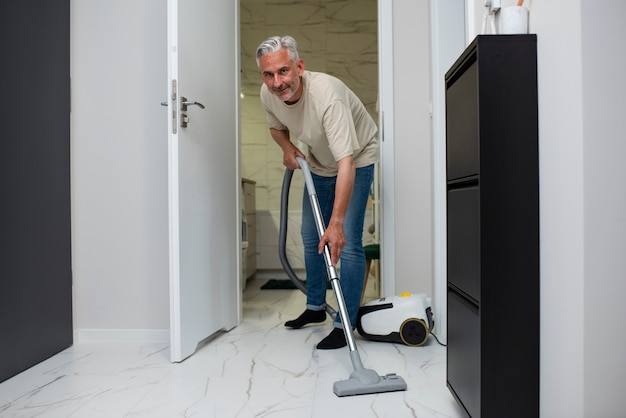 Full shot man vacuuming the floor