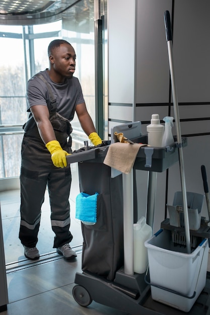 Full shot man walking with cleaning cart