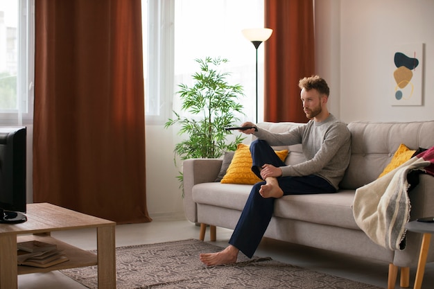 Full shot man watching news on tv