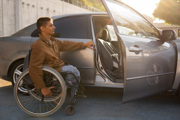 Full shot man in wheelchair near car