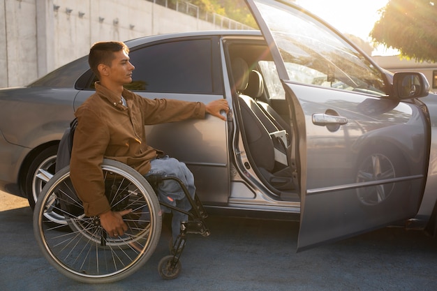 Full shot man in wheelchair near car
