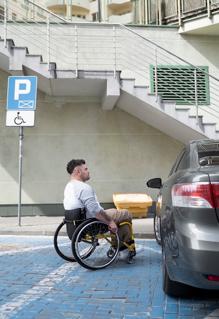 Free photo full shot man in wheelchair near car