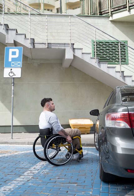 Full shot man in wheelchair near car